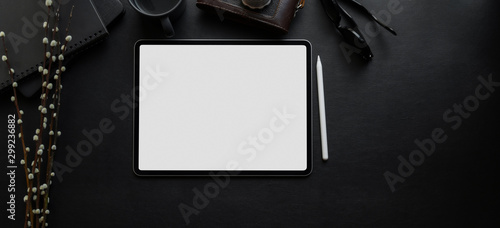 Top view of blank screen digital tablet on blank desk in dark luxury workspace