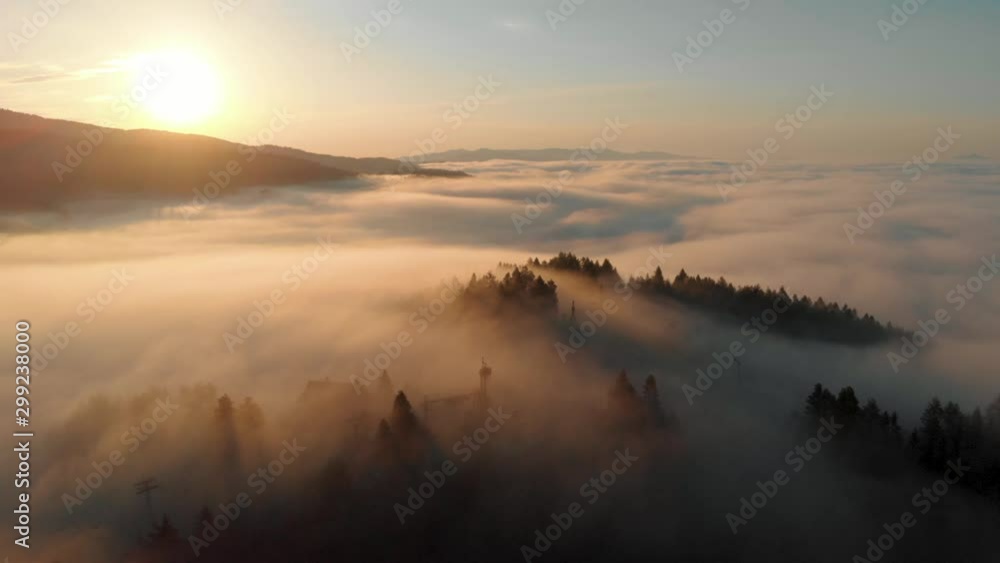 aerial shot of mountain top covered in clouds at sunrise with golden light aerial shot of mountain top covered in clouds at sunrise with golden light