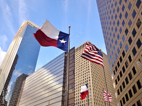 Low angle view of United States of America flag and Texas state flag in front of modern skyscrapers in downtown Houston (skyline / skyscrapers) on a summer day - Houston, Texas, USA  photo