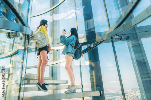 Two young Asian women traveler joy together taking photo on outdoor glass room, City travel Bangkok Thailand, Attractive tourists female on holidays vacation, Tourism beautiful destinations place Asia