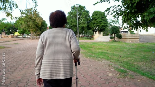 slow-motion of senior woman walking with walking stick in the park photo