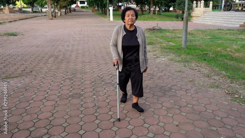 senior woman walking with walking stick in the park photo