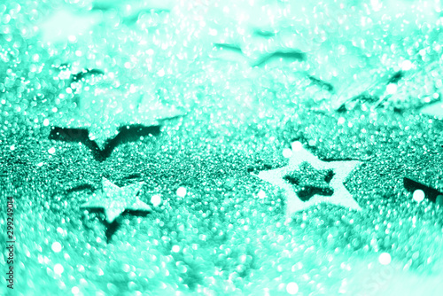 Christmas celebration. Abstract background for new year party. Patter of gold stars with lights, bokeh. Trendy green and turquoise color. Glitter stars in mint color
