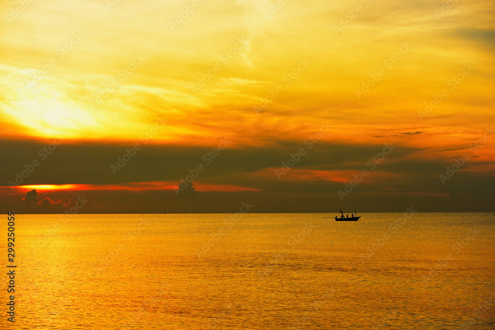 The view of the golden sky, the sea and a small fishing boat in the early morning, the sun is rising.