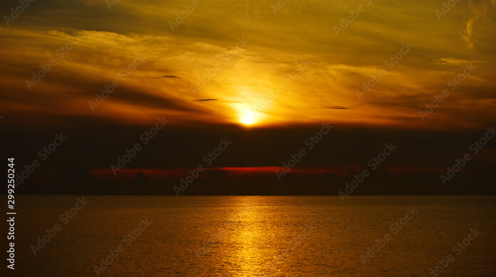 The view of the golden sky, the sea and a small fishing boat in the early morning, the sun is rising.	