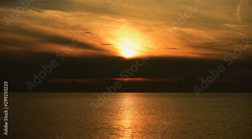 The view of the golden sky, the sea and a small fishing boat in the early morning, the sun is rising.