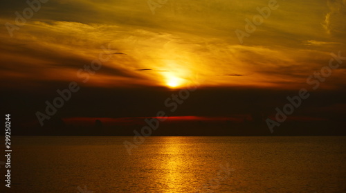 The view of the golden sky, the sea and a small fishing boat in the early morning, the sun is rising.  © tharathip
