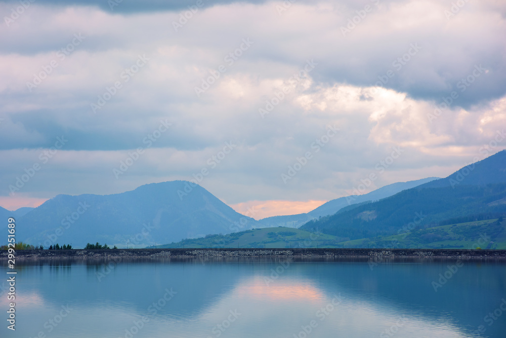liptovska mara lake in the evening. cloudy springtime weather above the distant mountains reflecting in the calm water. popular travel destination of slovakia