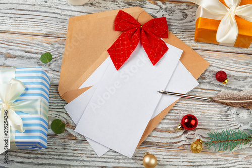 Close up of Christmas letter writing on yellow paper on wooden background with decorations photo