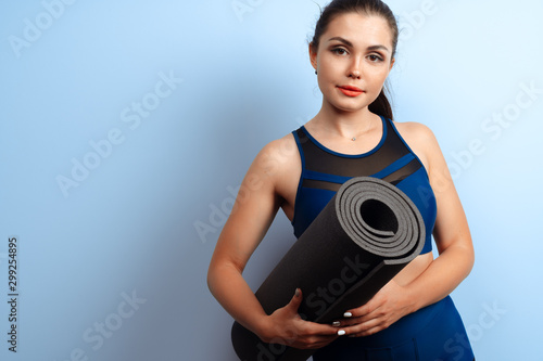 Young slim woman holding yoga fitness mat in her hands
