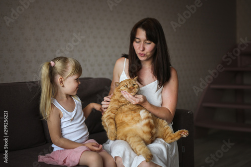 mom and daughter with big red fat cat on sofa