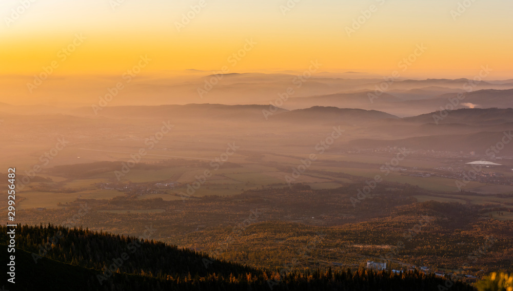 Beautiful colors of the sky at sunrise seen over the mountains and lowlands shrouded in fog. Characteristic landscape for the autumn season.