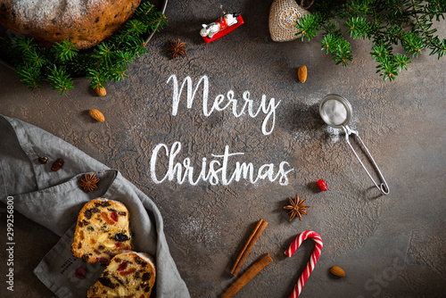 Merry Christmas text with festive decorations and Christmas fruit cake on gray background. Bakery christmas banner.