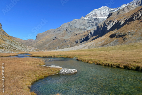 clear water of a river crossing alpine mountain with snowy peaks