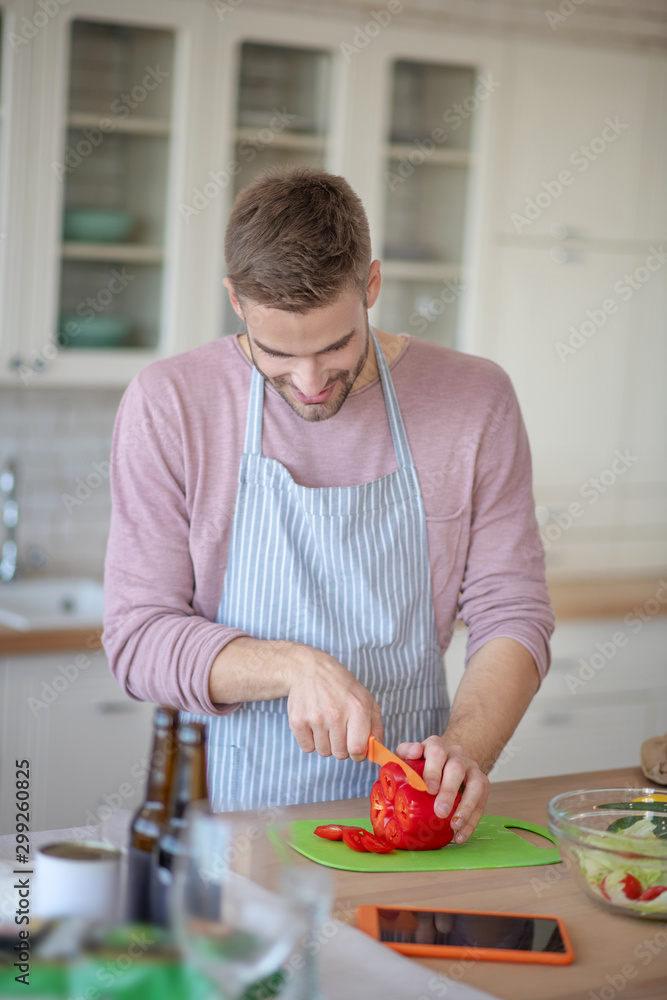 Dark-haired man slicing pepper while cooking vegetable salad Dark-haired man slicing pepper while cooking vegetable salad