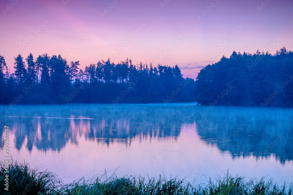 Magical dawn over the lake with a beautiful reflection on the water. Serene lake in the early morning. Nature landscape