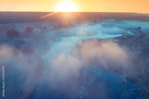 Early misty morning. Sunrise over the lake. Rural landscape in summer. Aerial view