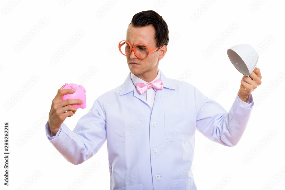 Portrait of crazy young man doctor playing with piggy bank Portrait of crazy young man doctor playing with piggy bank