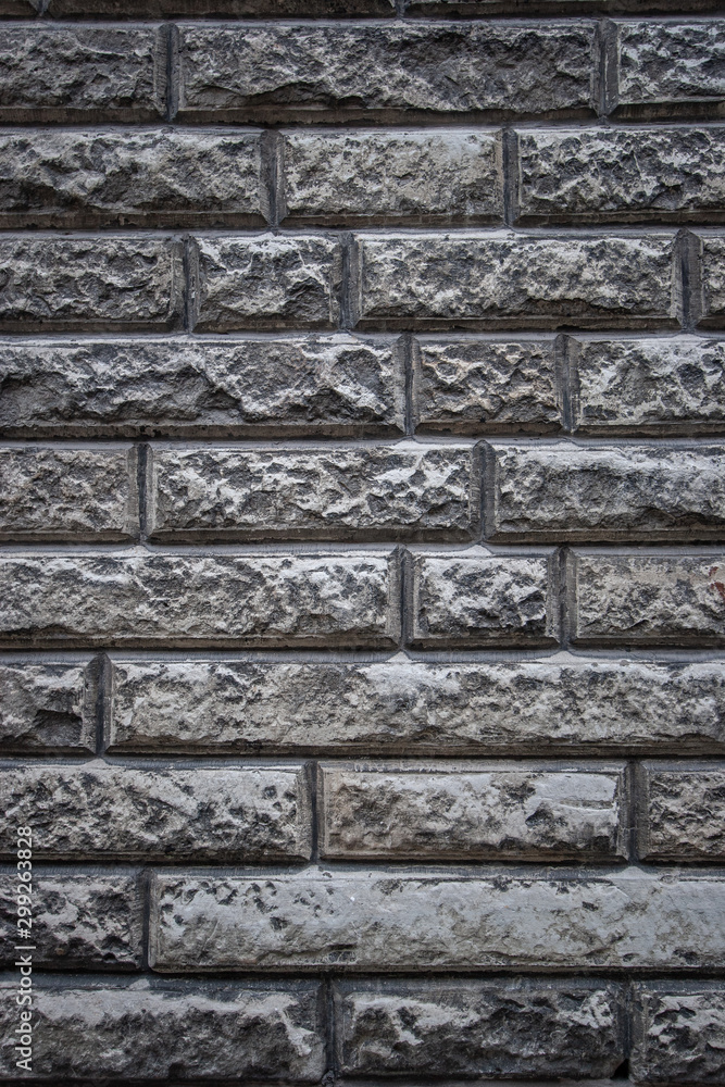 Textural background of natural stone laid in the wall. Grey colour. Vertical frame.