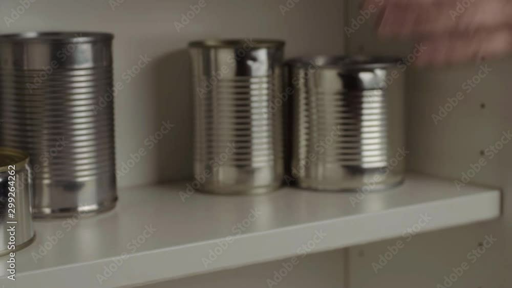 Stacking aluminum tin cans out of food cupboard shelf Stacking aluminum tin cans out of food cupboard shelf