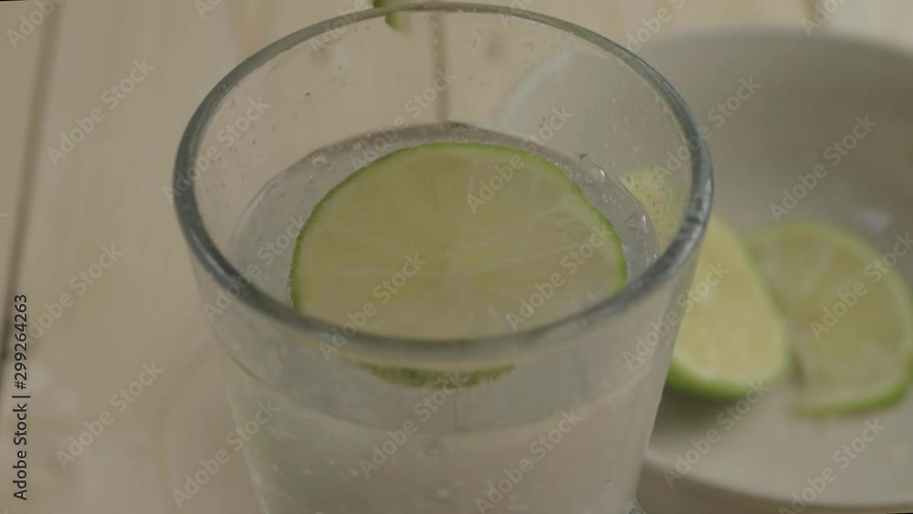 Dropping lime slices into a refreshing glass of fizzy water Dropping lime slices into a refreshing glass of fizzy water
