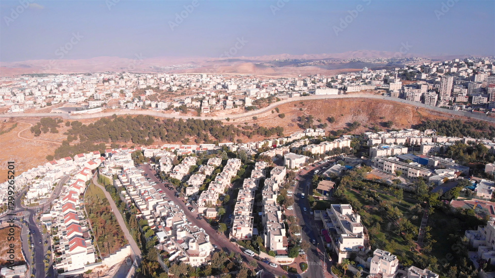 Wide Aerial footage of Israel and Palestine town divided by fence with Judean desert mountains  