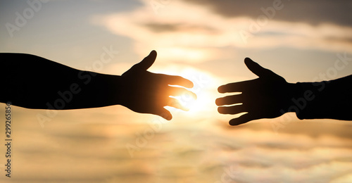 Mercy, two hands silhouette on sky background, connection or help concept. The outstretched hands, salvation, help silhouette, concept of help. Giving a helping hand. Rescue, helping gesture or hands