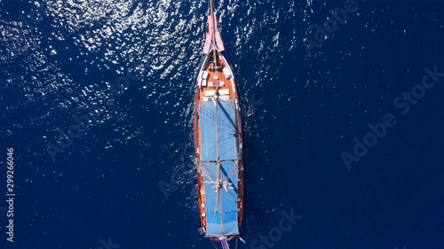 Tourists tour on old style pirate ship on calm clear drak blue sea Aerial top down view