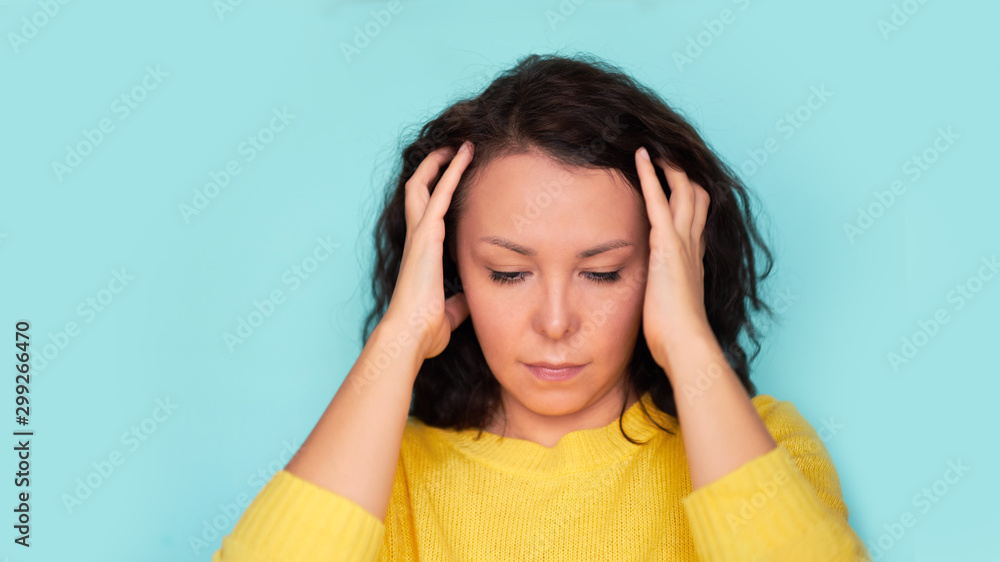 Young Asian girl scratches her hair on a blue background. headache Young Asian girl scratches her hair on a blue background. headache