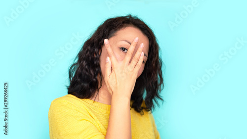 cheerful female covering her face using hands on a blue background