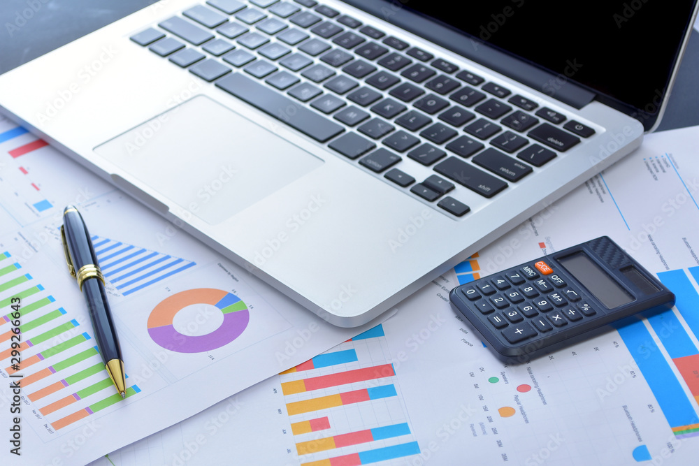 Laptop and pen with business charts, graphs, statistic and documents background for business and finance concepts Laptop and pen with business charts, graphs, statistic and documents background for business and finance concepts