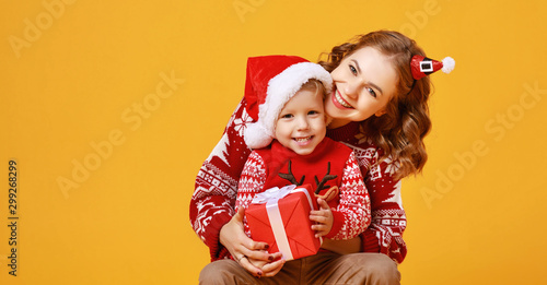 happy family mother and child son with christmas gifts on yellow background