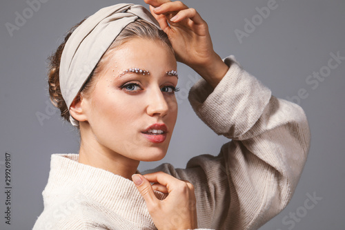 Young woman with creative eyebrows on grey background