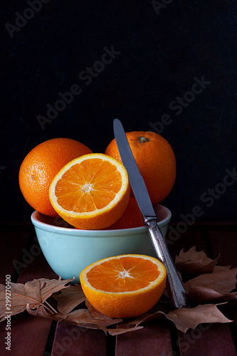 ORANGE IN BOWL WITH KNIFE NEXT TO TREE LEAVES ON DARK BACKGROUND 4. AUTUMN FRUIT