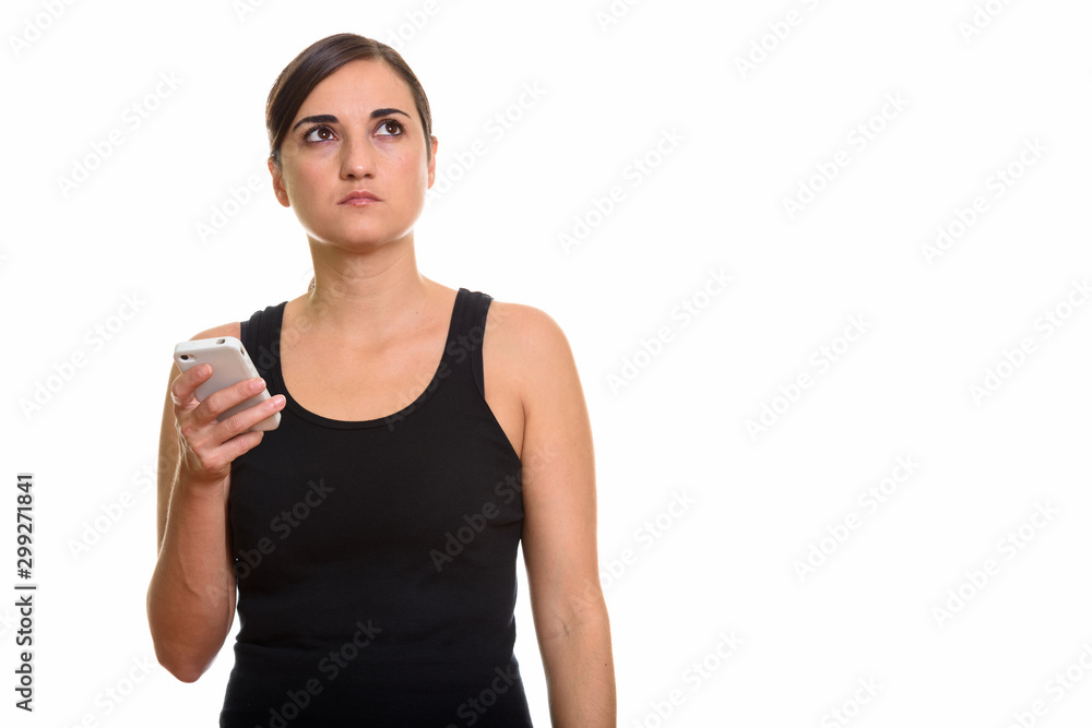 Studio shot of beautiful woman holding mobile phone while thinking Studio shot of beautiful woman holding mobile phone while thinking