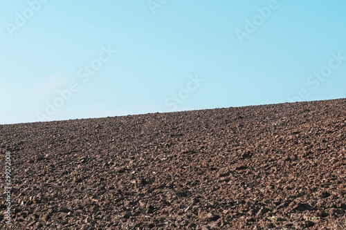 Field plowed, sown cereals. Agriculture plowed field in spring day. Black soil plowed field. Plowed field with blue sky