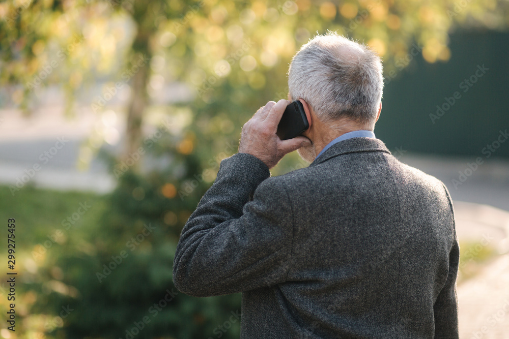 Back view of elderly man speak by the mobile phone outside Back view of elderly man speak by the mobile phone outside