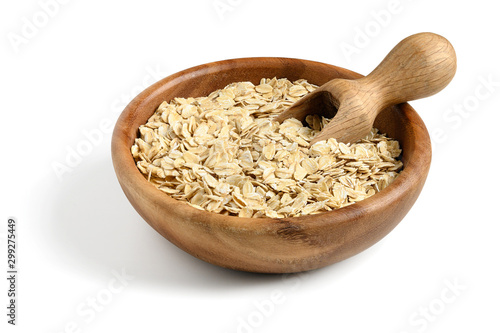 Oat flakes with wooden scoop in wooden bowl isolated on white.
