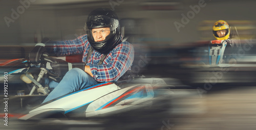 Portrait of male racer in helmet driving kart on track