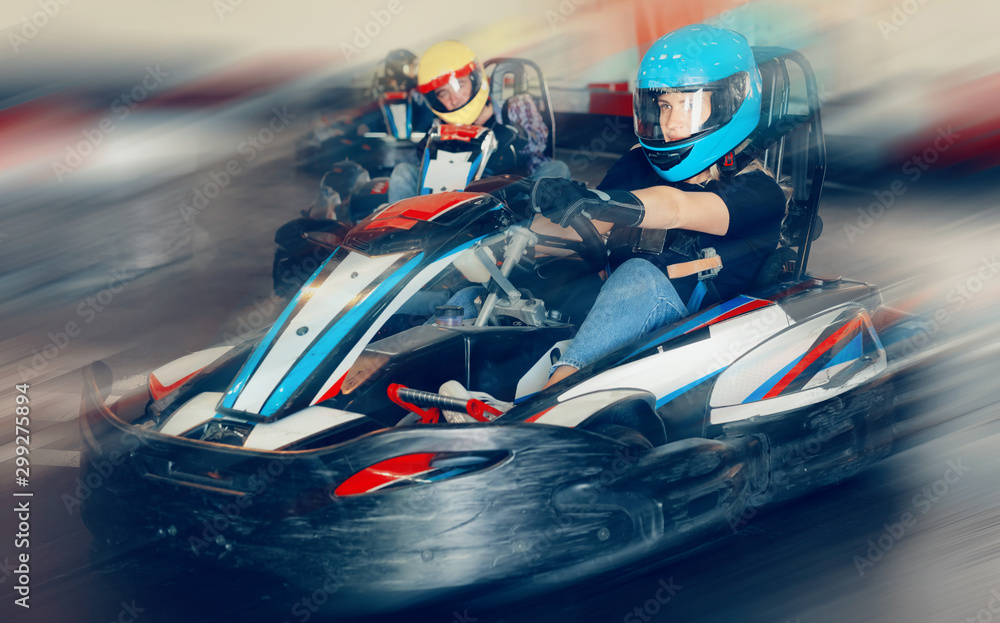 Female racer in helmet driving kart on track
