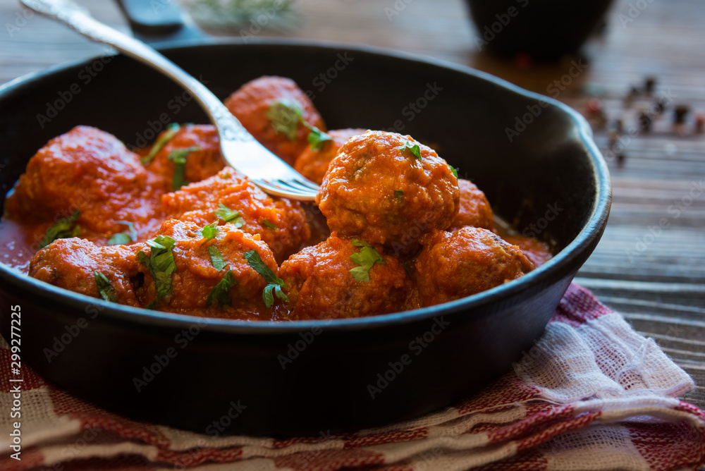 Homemade meatballs with tomato sauce and parsley in a frying pan Homemade meatballs with tomato sauce and parsley in a frying pan
