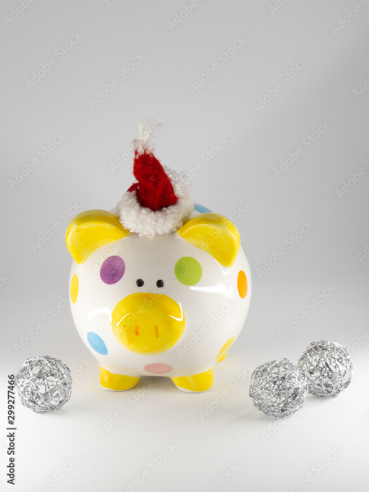 Colorful piggy bank with santa hat surrounded by silver ornaments isolated on white background Colorful piggy bank with santa hat surrounded by silver ornaments isolated on white background