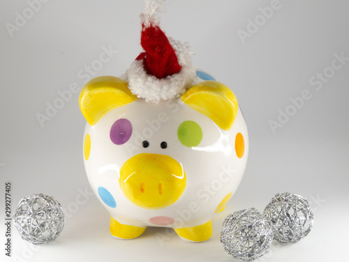 Colorful piggy bank with santa hat surrounded by silver ornaments isolated on white background