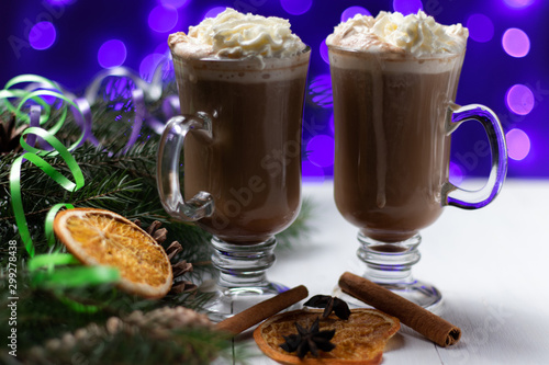 two cups of cappuccino with cream of cocoa winter new year fir tree cones bokeh blur holiday lights