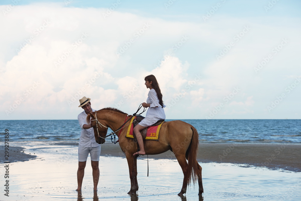 Couples are happily riding horses on the sandy beach Couples are happily riding horses on the sandy beach