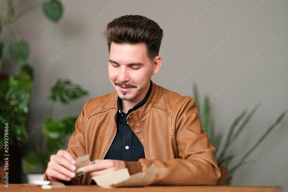 Young guy makes cigarette with hand rolling tobacco Young guy makes cigarette with hand rolling tobacco
