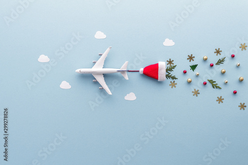 Christmas composition. Airplane flying in sky clouds fir star santa hat top view background with copy space for your text. Flat lay.