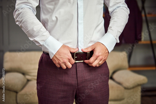 Businessman putting on a belt, fashion and clothing concept,groom getting ready in the morning before ceremony