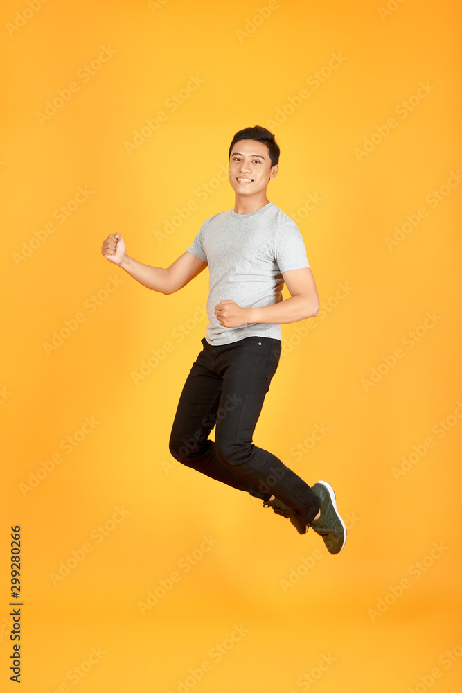 Handsome jumping Asian man on color background Handsome jumping Asian man on color background