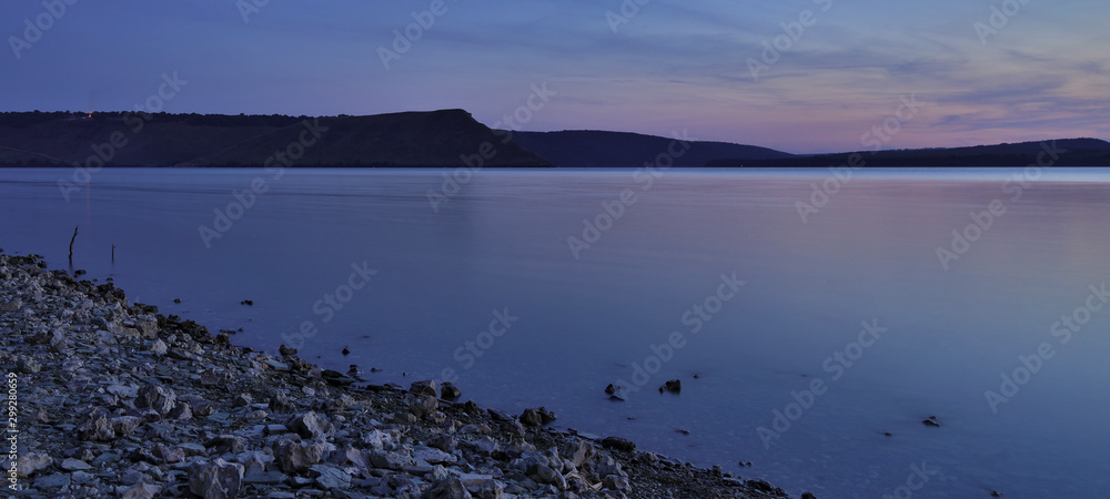 panorama long exposure scenic shore line of smooth lake water surface in peaceful twilight time lighting after sunset, empty copy space for your text here